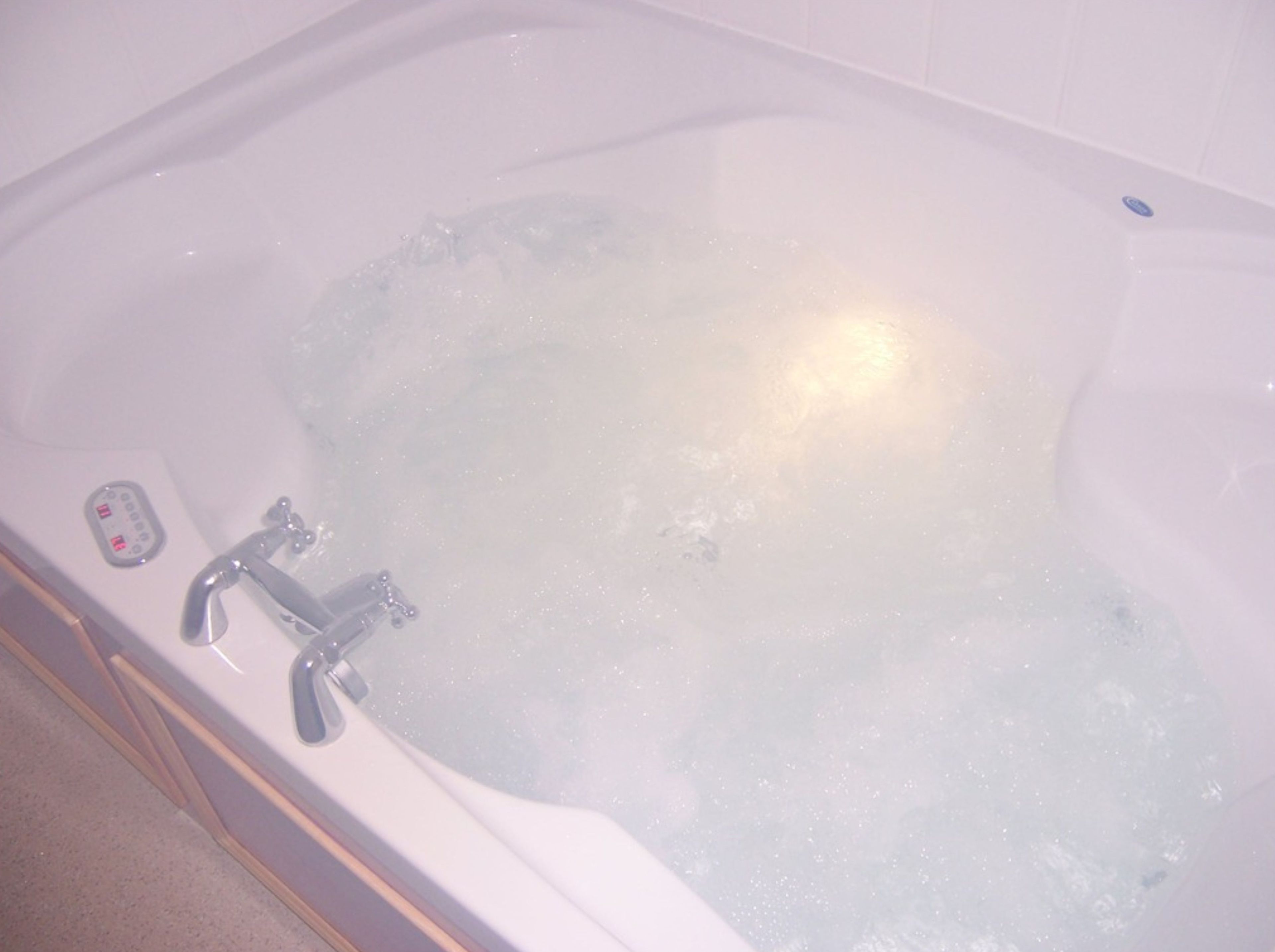 Une baignoire dotée d’un panneau de commande et de deux robinets.