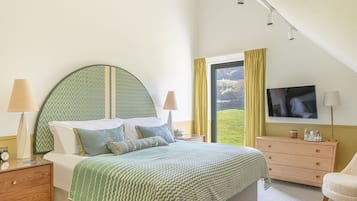 A bedroom with a bed, nightstands, a dresser, a TV, and a window with curtains.
