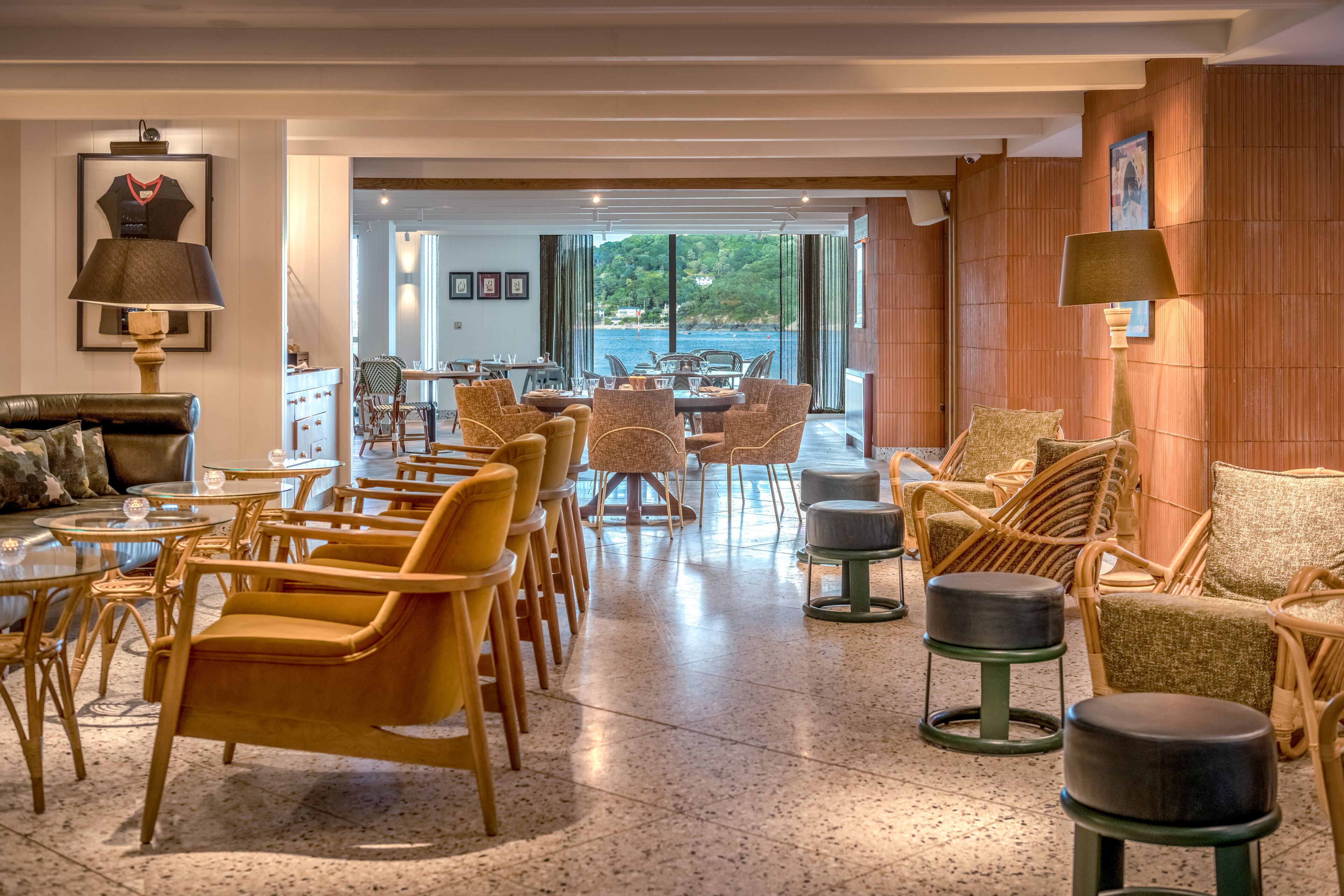 A spacious lounge area with wicker furniture, a dining table, and a view of the outdoors.