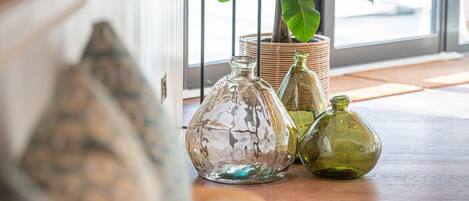 A wooden table with three glass bottles and a woven basket with a plant.