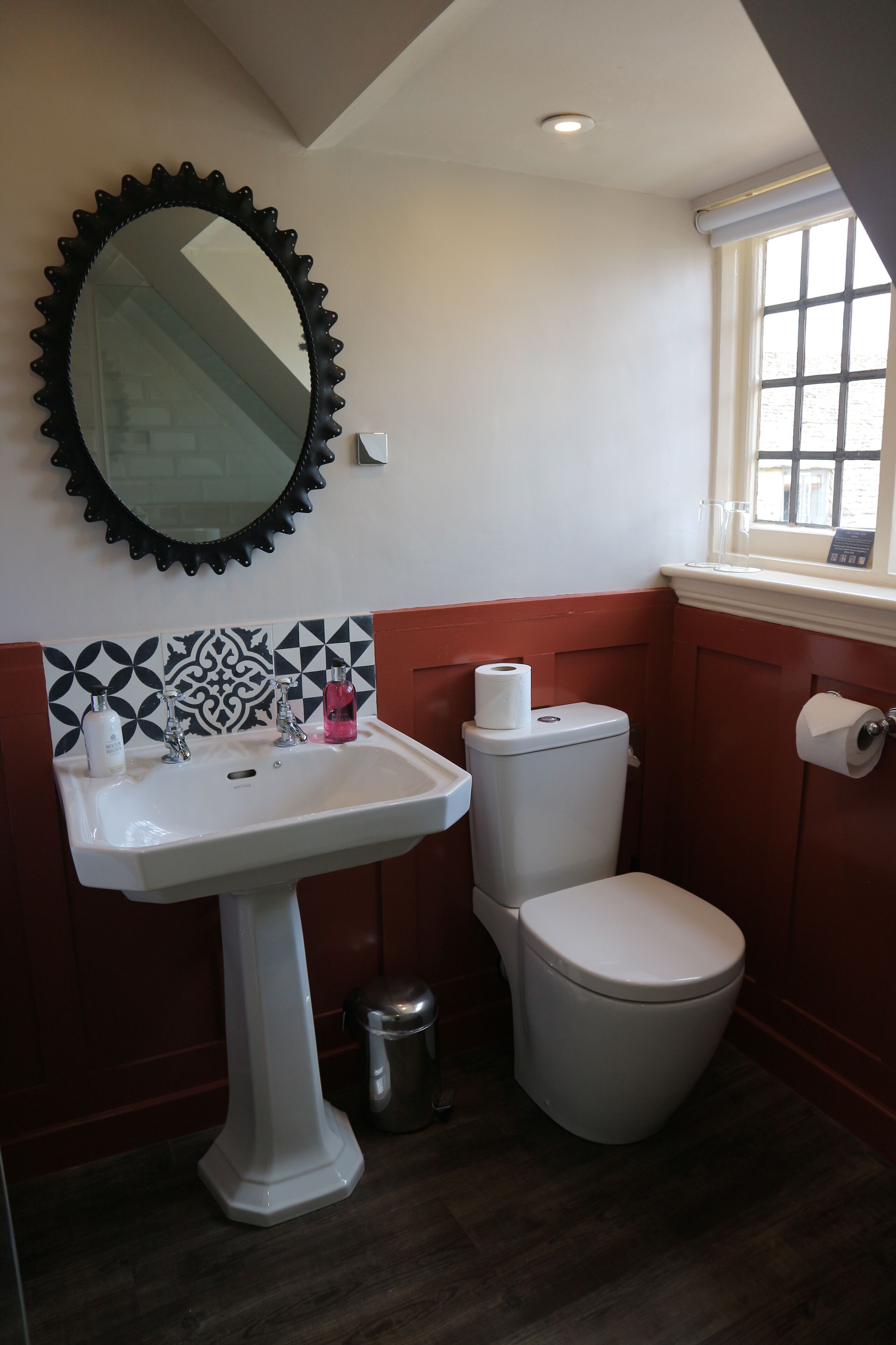 Une salle de bain avec un lavabo blanc, des toilettes et un miroir avec un cadre noir.