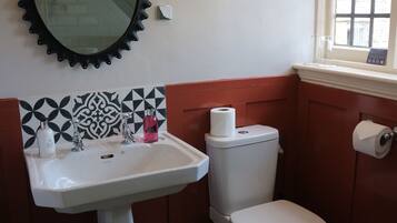 Une salle de bain avec un lavabo blanc, des toilettes et un miroir avec un cadre noir.