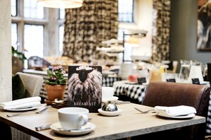 A breakfast setting with a table set for two, including plates, cups, cutlery, and a menu. - The Lamb Inn (Burford)