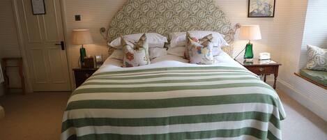 A neatly made bed with a striped bedspread, a patterned headboard, and two bedside lamps.