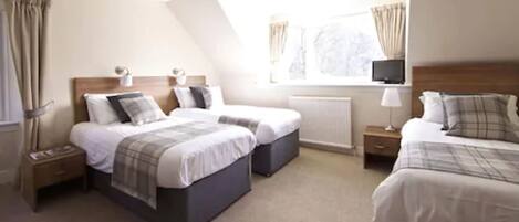 A hotel room with two beds, a TV, and a window with curtains.