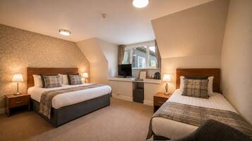 A hotel room with two beds, a desk, and a window.