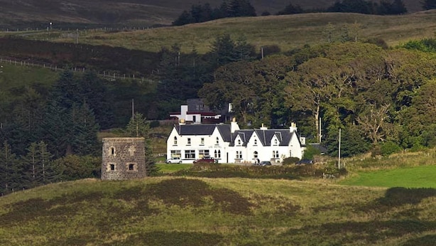 A large white building with multiple windows and a stone structure nearby.