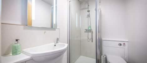 A modern bathroom with a glass-enclosed shower, a white sink, and a toilet.