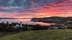 A coastal landscape with a church, a calm lake, and a sunset.