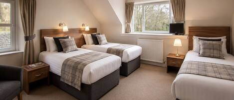 A hotel room with two beds, a television, and a window with curtains.