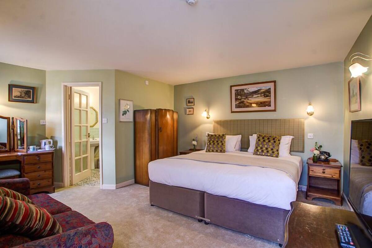 A bedroom with a large bed, a dresser, a nightstand, and a chair.