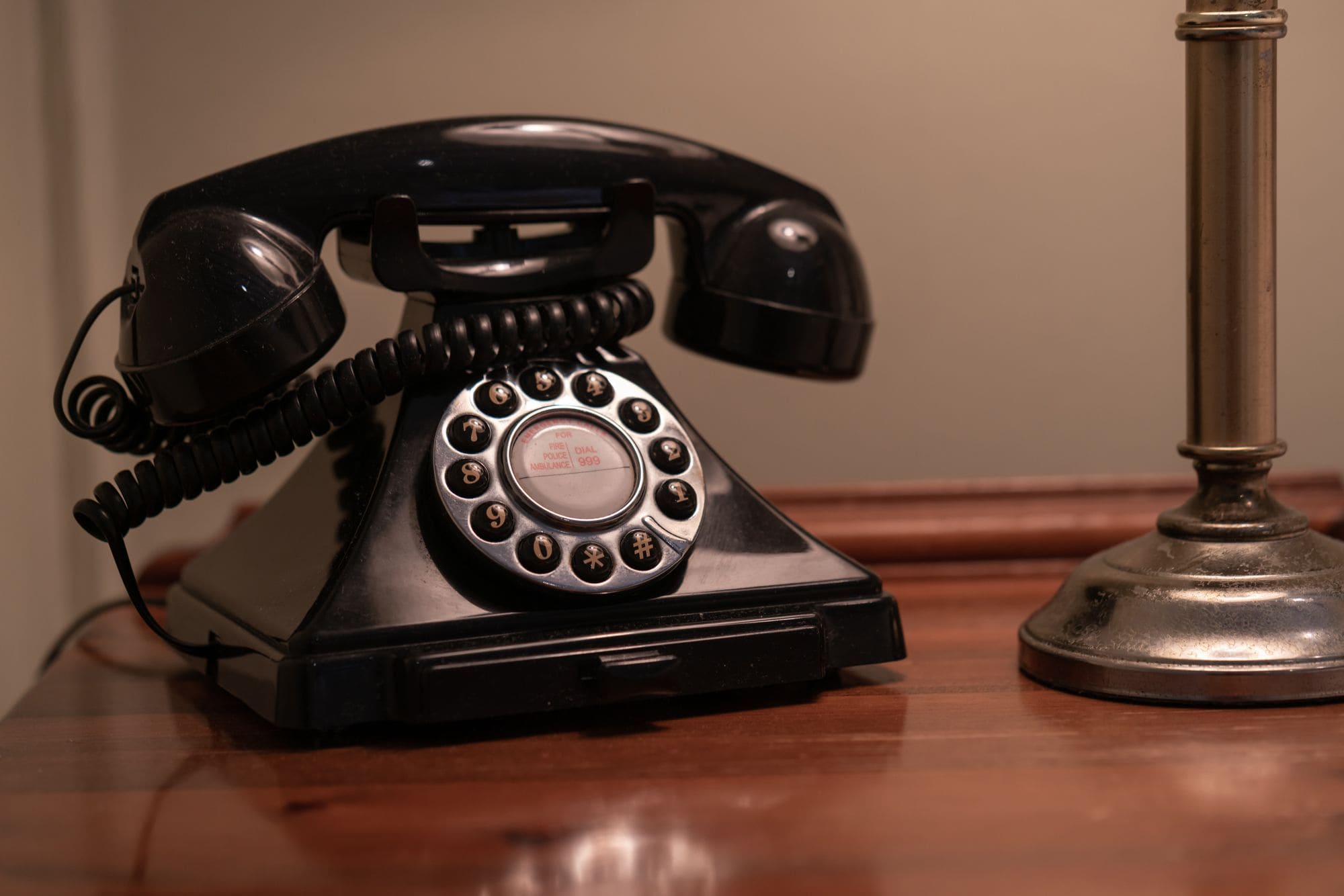 Un teléfono antiguo de disco giratorio negro sobre una mesa de madera.