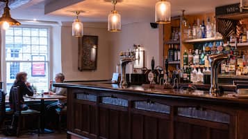 A bar area with a wooden counter, multiple taps, and a variety of bottles.