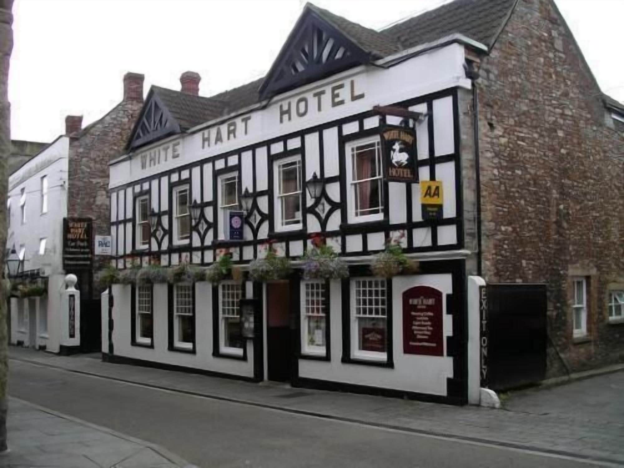 Um edifício tradicional em estilo de enxaimel com a placa "White Hart Hotel" sobre a entrada.