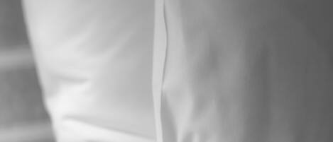 Primer plano de una cama blanca con un almohadón ordenado.