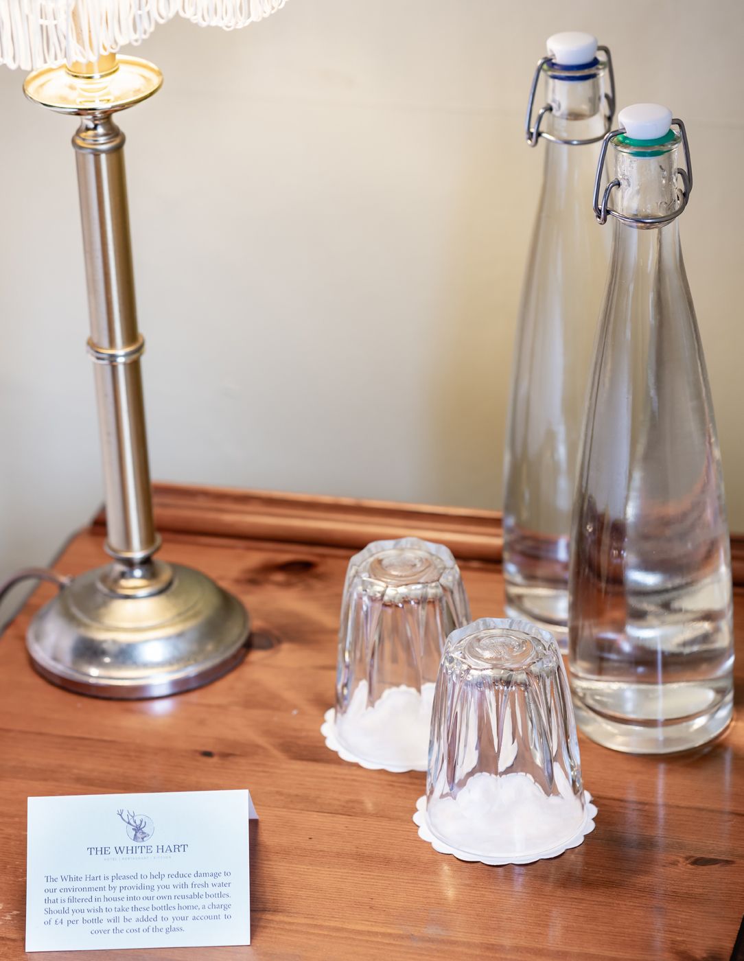 A table with a lamp, two glass bottles, and a salt shaker set. A sign reads "The White Hart".