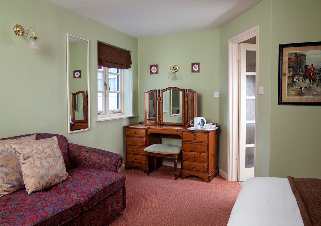 A bedroom with a bed, a dresser with a mirror, a window with a brown valance, and a painting on the wall.