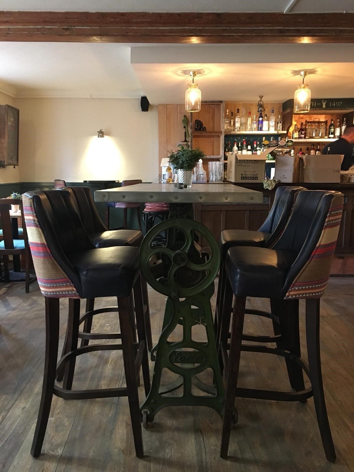 A bar area with a central island, bar stools, and a variety of bottles and glasses on shelves.