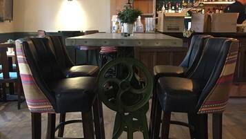 A bar area with a central island, bar stools, and a variety of bottles and glasses on shelves.