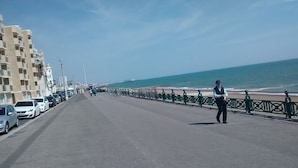 A coastal road with parked cars, a pedestrian walkway, and a person standing by the railing. - Seafield House (Hove)