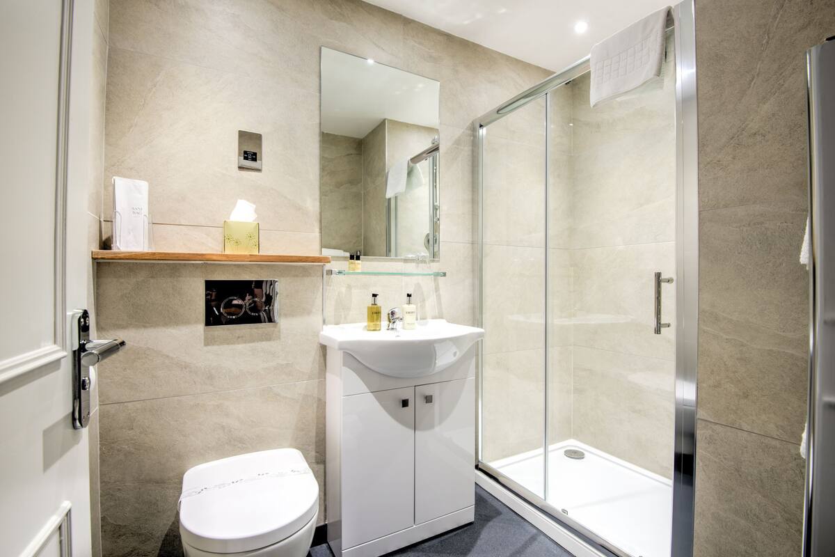 Une salle de bain moderne équipée de toilettes, d’une douche à parois de verre et d’un meuble-lavabo avec un miroir.