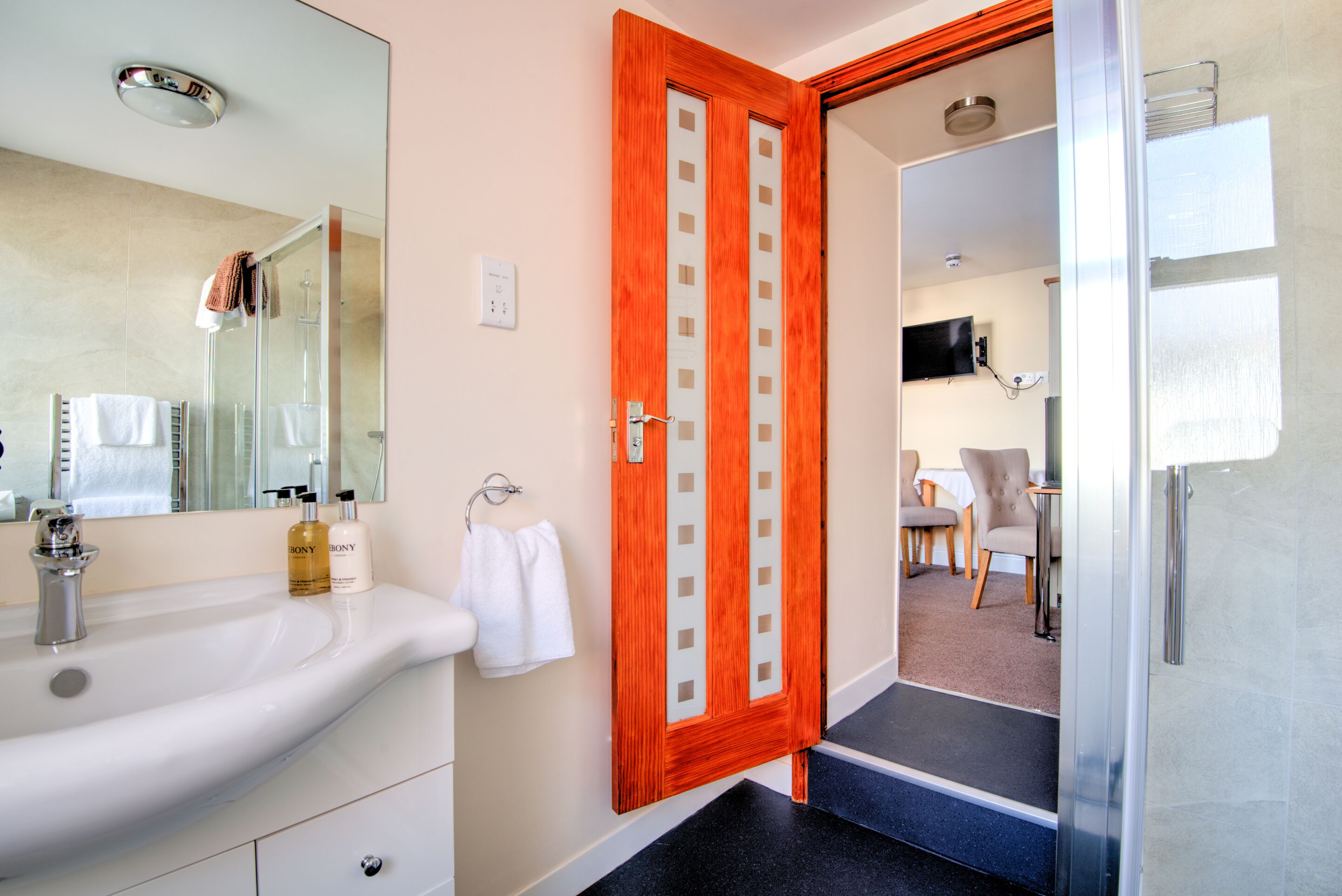 A bathroom with a sink, mirror, and a wooden door.