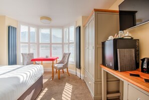 Une chambre d’hôtel comprenant un lit, une table à manger, une chaise, une armoire et un coin cuisine.
