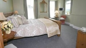 A bedroom with a bed, bedside tables, a mirror, and a window. - The Pack Horse (South Brent)