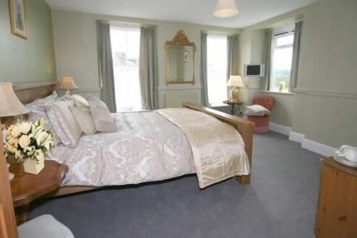 A bedroom with a bed, bedside tables, a mirror, and a window.