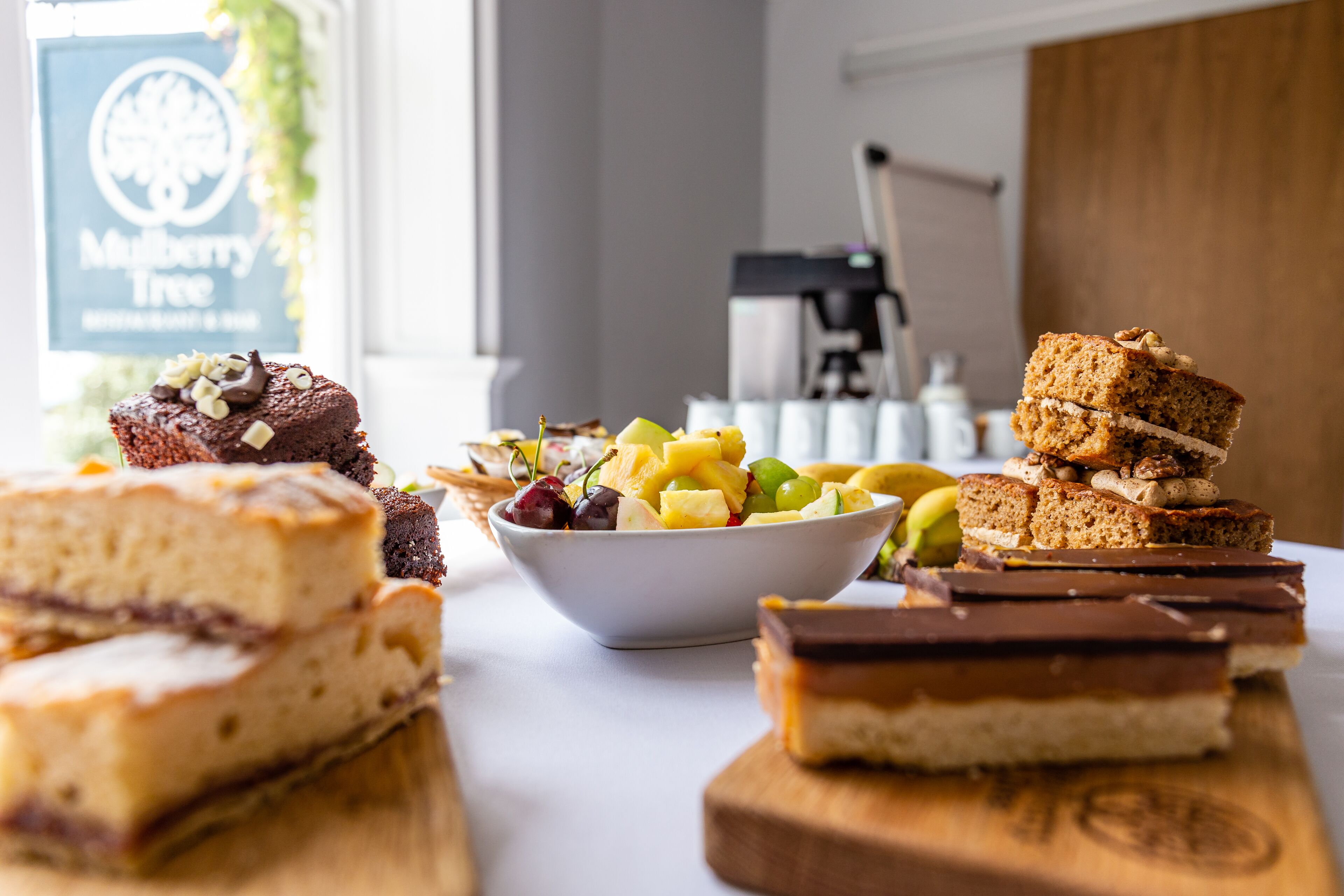 Diversos doces sobre uma mesa, incluindo bolos e uma saladeira de frutas.