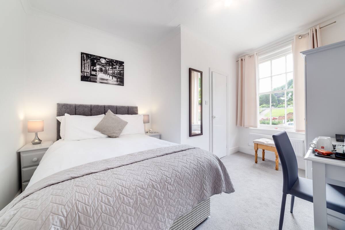 A bedroom with a bed, bedside tables, a desk, and a chair.