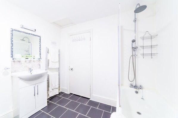 A modern bathroom with a white sink, mirror, and shower.