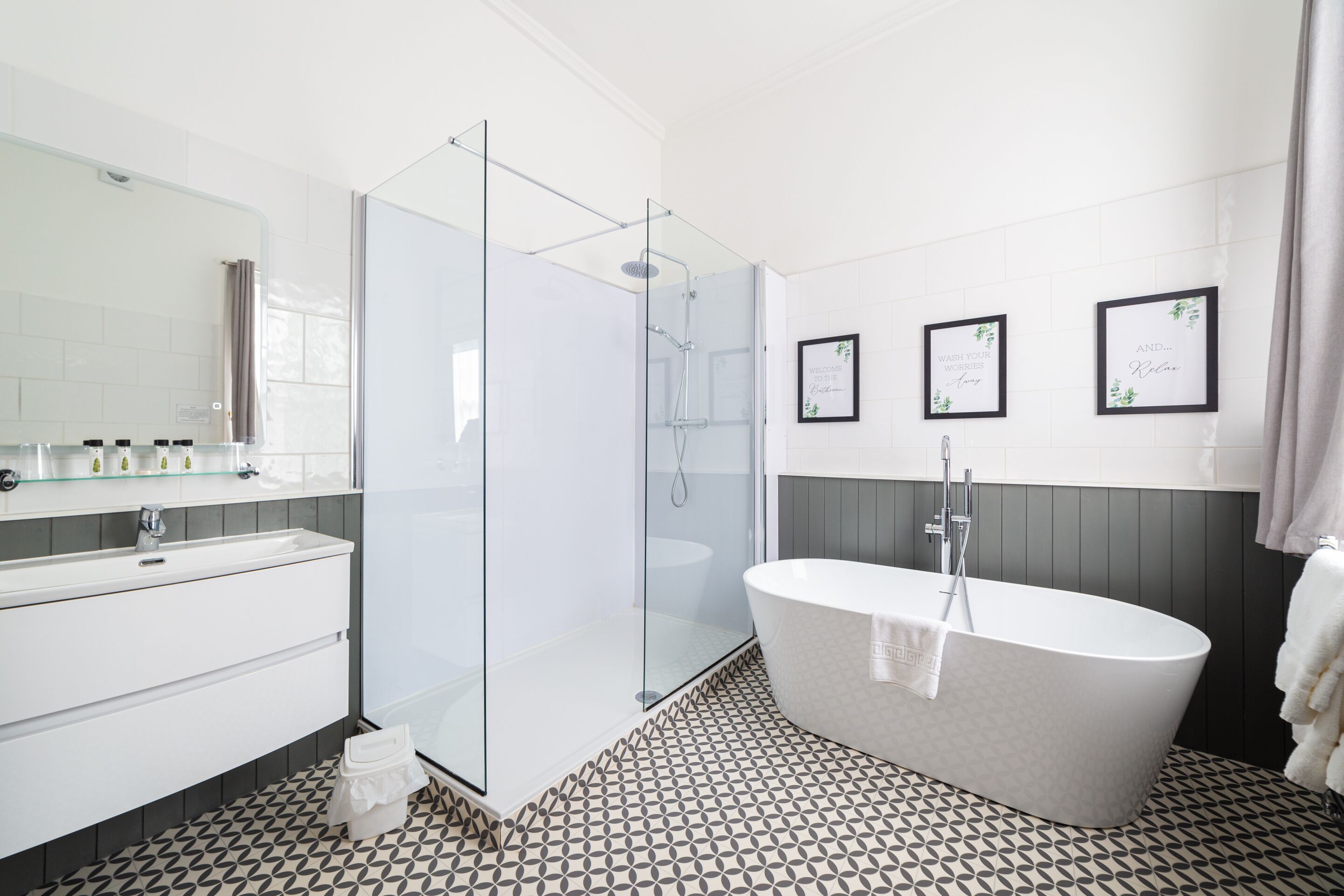 Une salle de bain moderne dotée d’une douche à parois de verre, d’une baignoire sur pieds et d’un meuble-lavabo avec un miroir et un plan de travail.