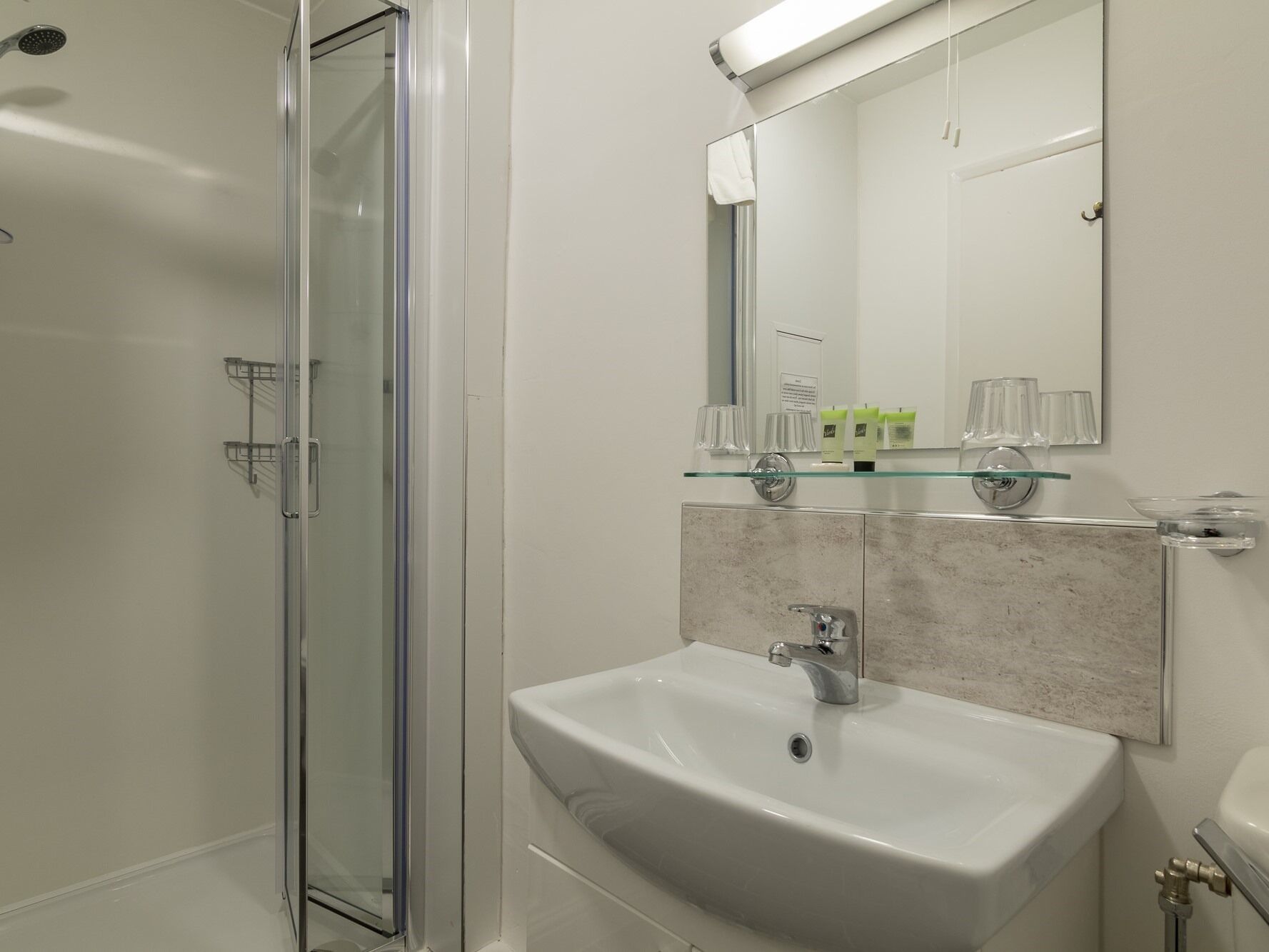 Un baño moderno con cabina de ducha de vidrio, un lavabo blanco y un espejo encima.
