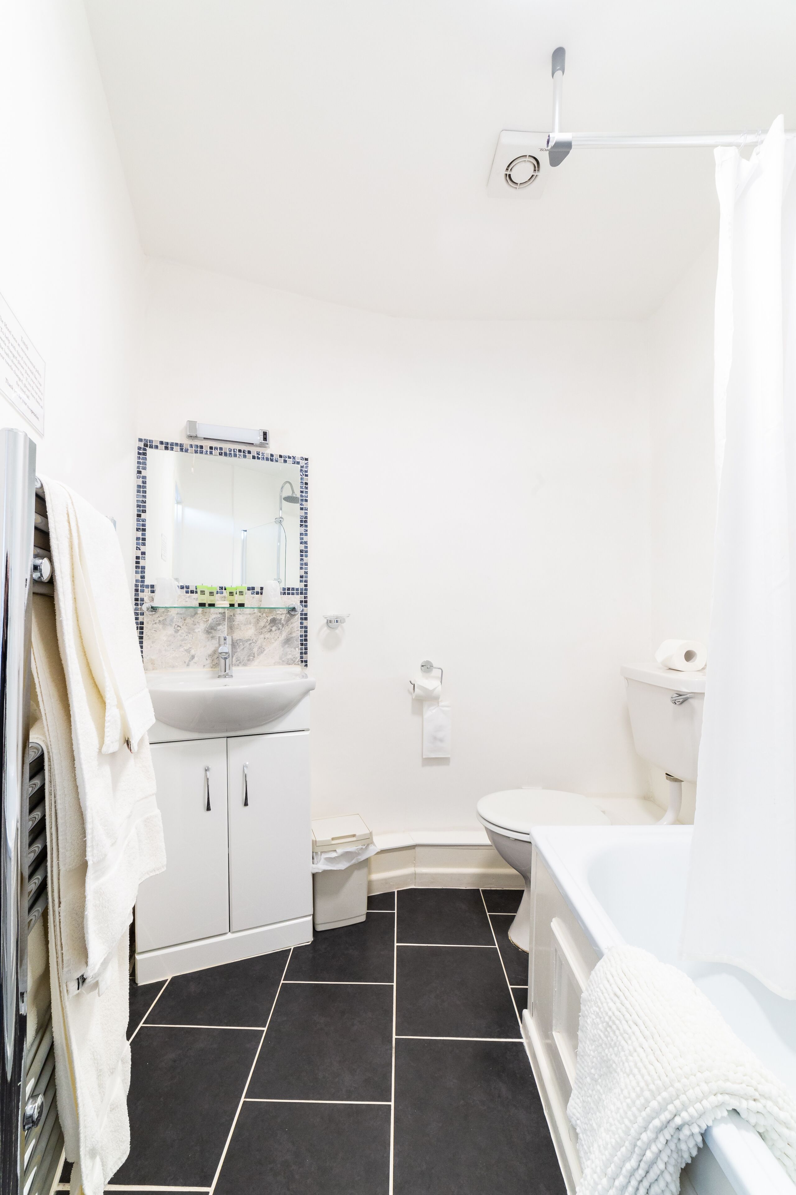 A bathroom with a white sink, mirror, toilet, and bathtub.