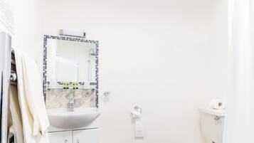 A bathroom with a white sink, mirror, toilet, and bathtub.
