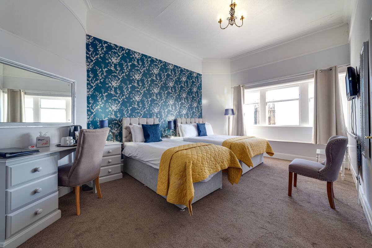 A bedroom with a large bed, a desk, a chair, and a TV.