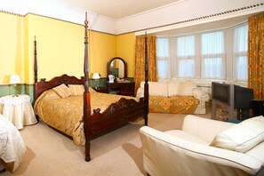 A bedroom with a four-poster bed, a sofa, a television, and a window with curtains. - Meare Manor (Glastonbury)