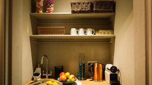 Una kitchenette equipada con un lavamanos, una cafetera, un hervidor y un frutero.