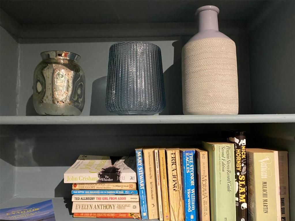 Una estantería con libros y jarrones decorativos.