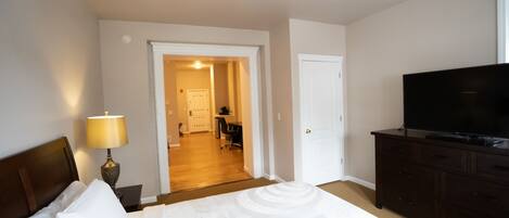 A hotel room with a bed, a TV, a desk, and a lamp.