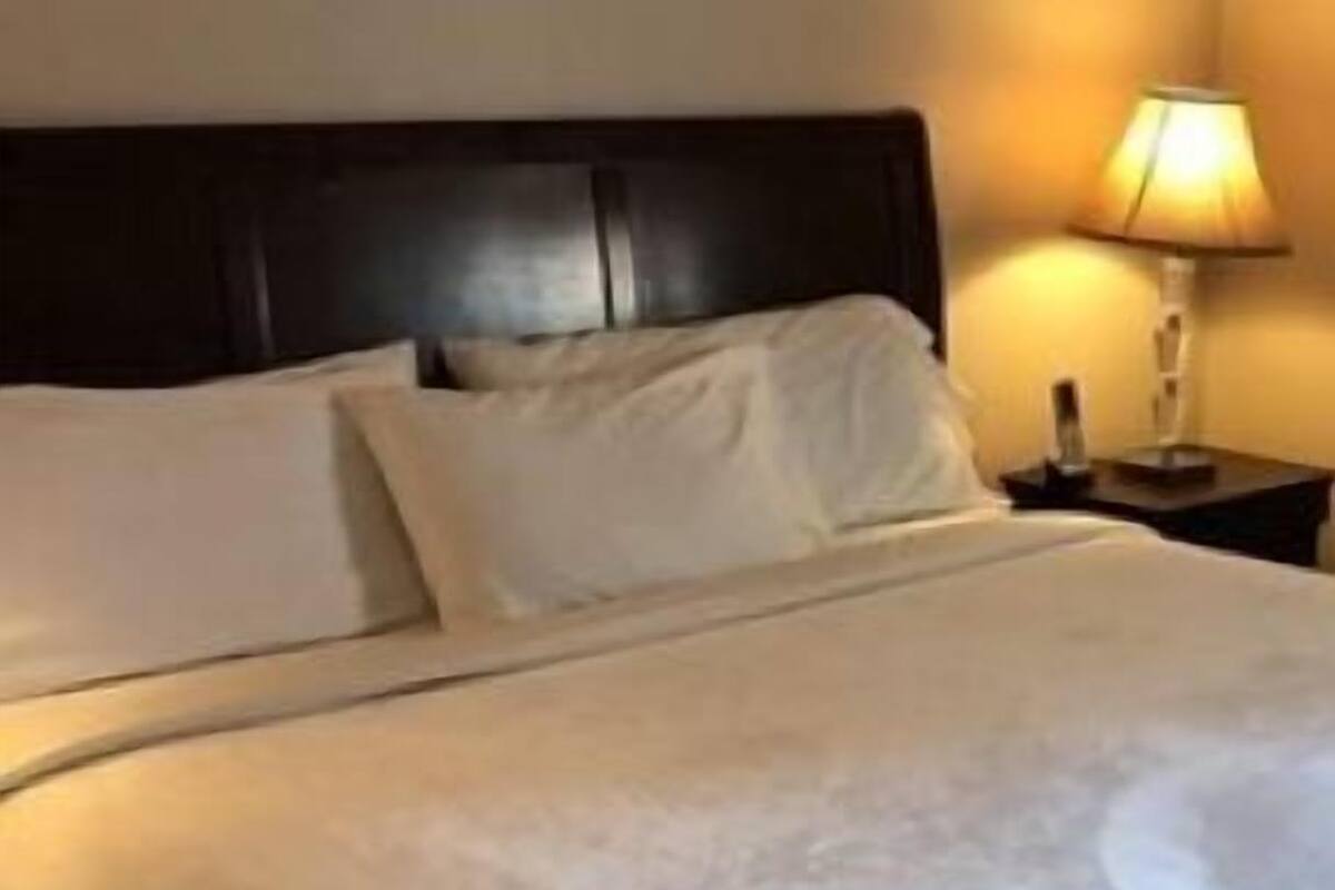 Ein ordentlich bezogenes Bett mit weißen Leinen in einem Hotelzimmer.