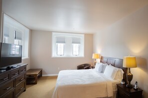 A hotel room with a bed, bedside tables, a TV, and a window with blinds. - Amsterdam Castle (Amsterdam)