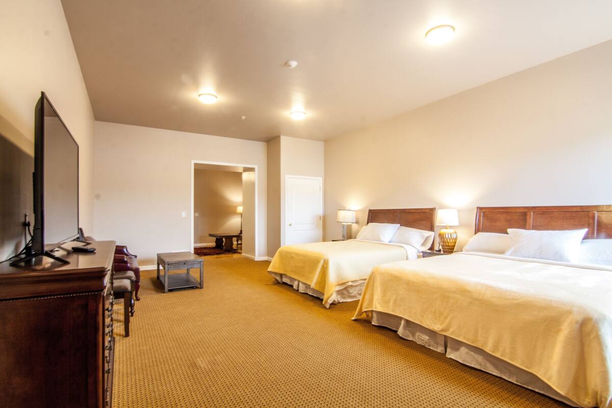 Ein Hotelzimmer mit zwei Betten, einem Schreibtisch, einem Fernseher und einem kleinen Tisch.