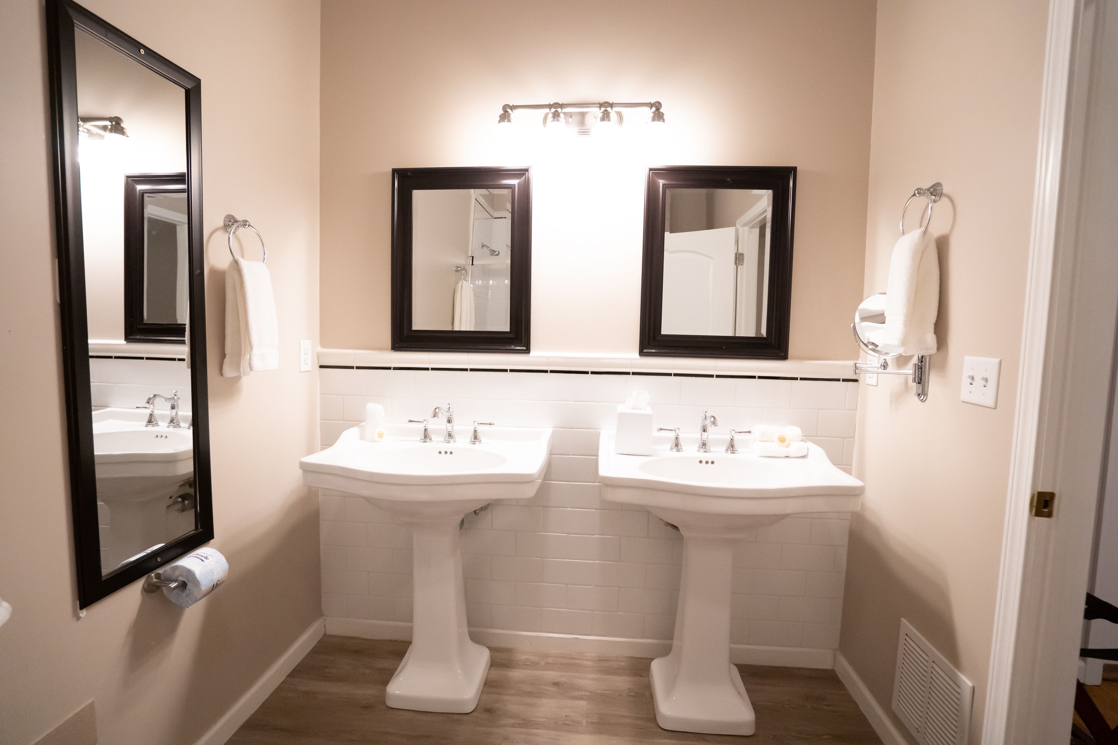 A bathroom with two sinks, a large mirror, and a towel rack.
