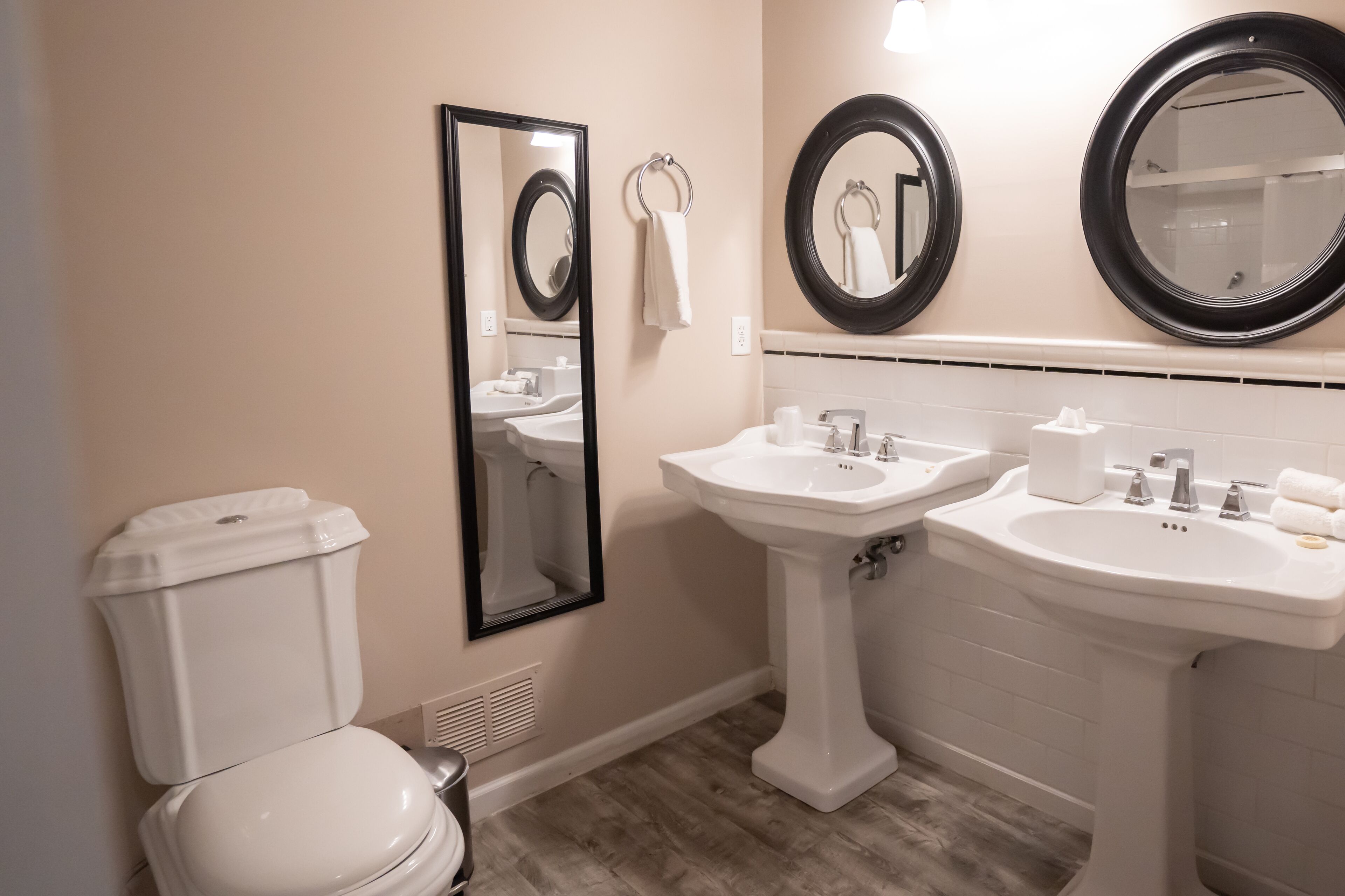 A bathroom with a toilet, two sinks, and three mirrors.