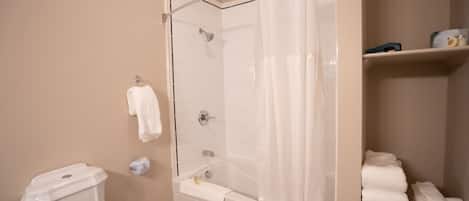 Ein Badezimmer mit Dusche, Toilette und einem Handtuchregal.