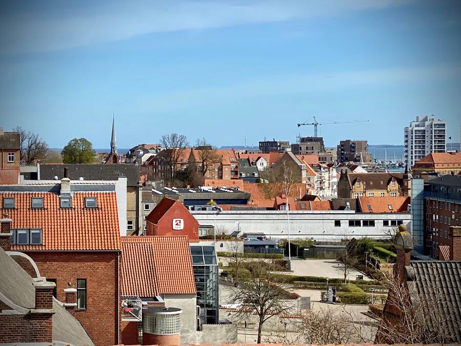 A cityscape with a mix of traditional and modern architecture, including a prominent building with a red roof and a bank sign.