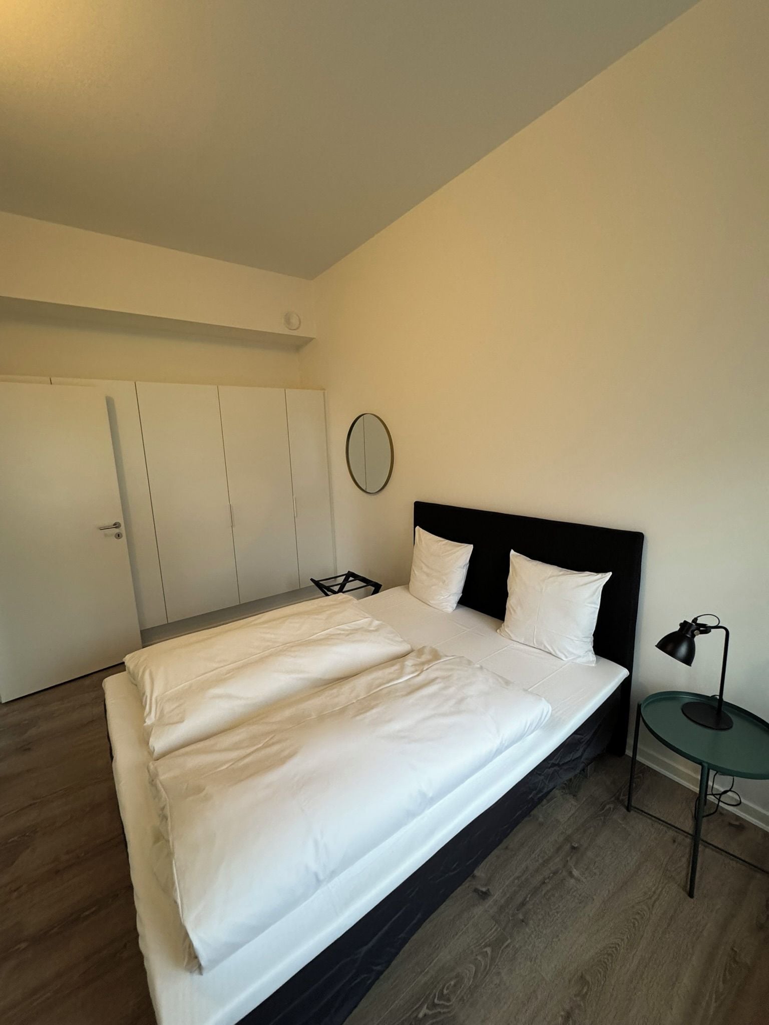 Ein Schlafzimmer mit einem Bett, einem Nachttisch, einer Lampe und einem Kleiderschrank.