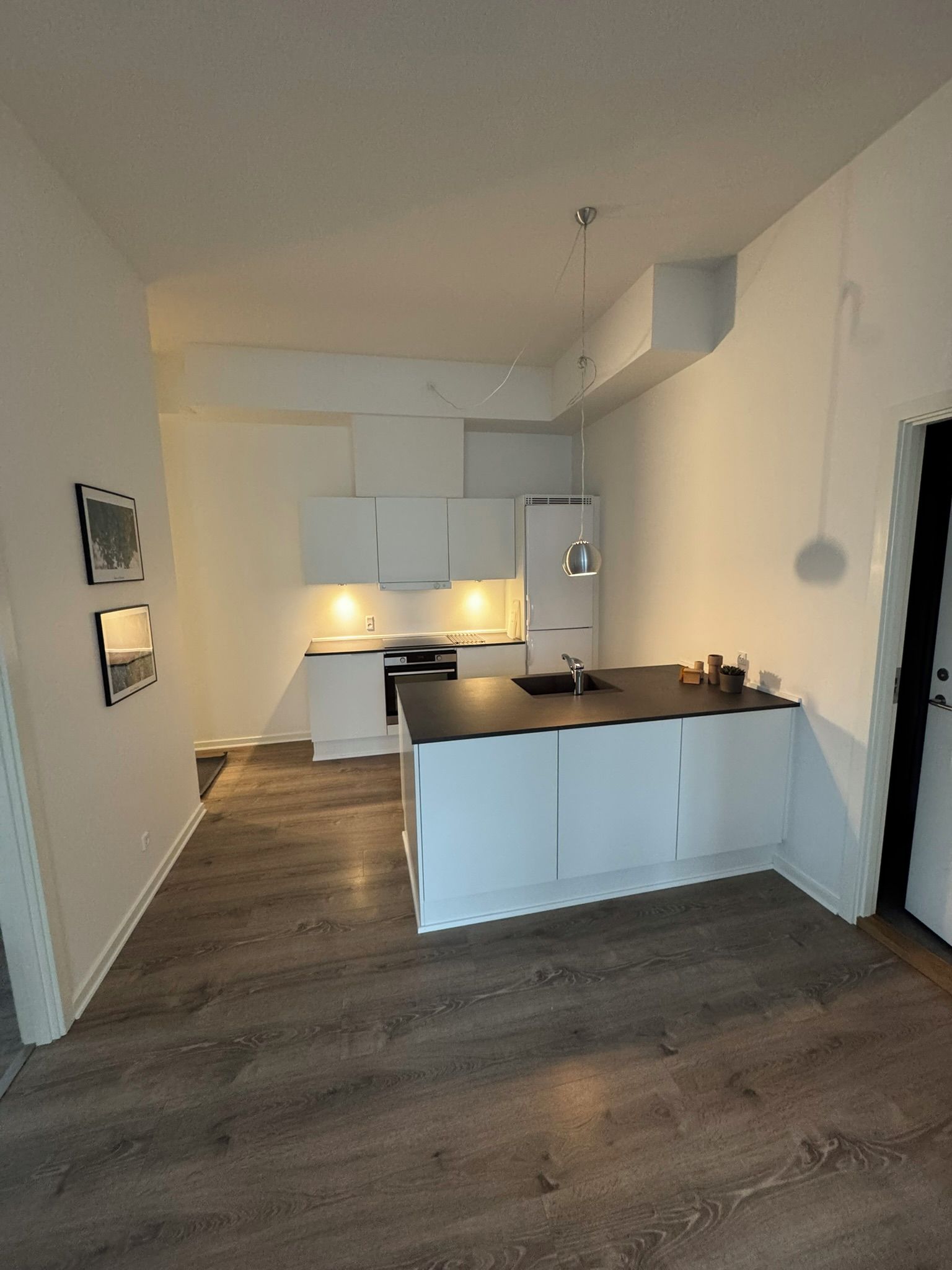 Une cuisine moderne avec des meubles blancs, un îlot central et un four encastré.